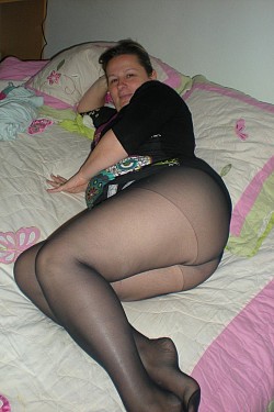 Chubby girl in black pantyhose poses on the bed